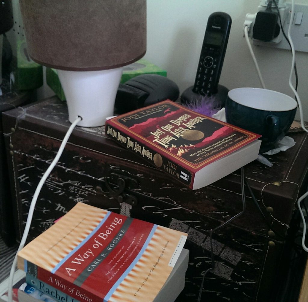 side table with books, a lamp, a cup and a telephone