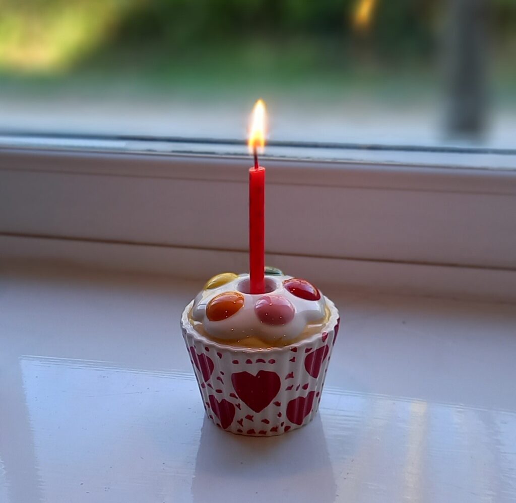 Ceramic candle holder shaped like a cup cake with a lit candle in the centre