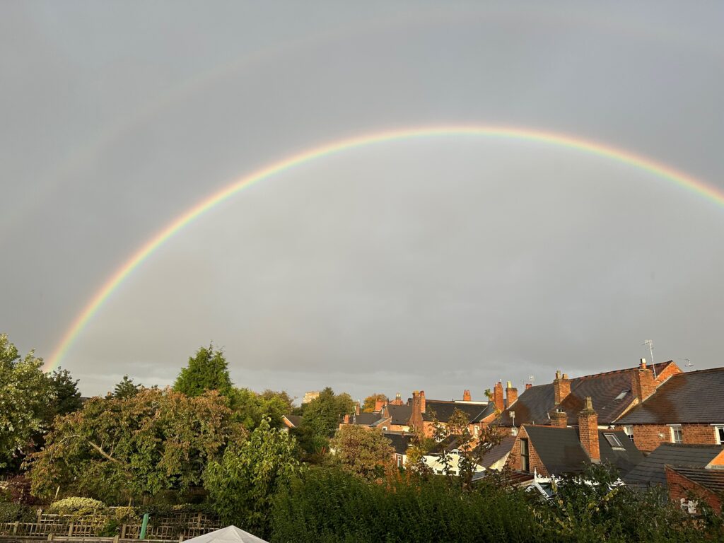 Houses and trees on horizon with grey sky and full rainbow. Image for hot to recover from a bad relationship