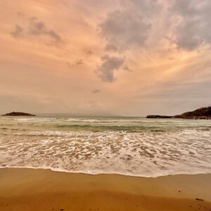 Beach in foreground, orange sky at sunset