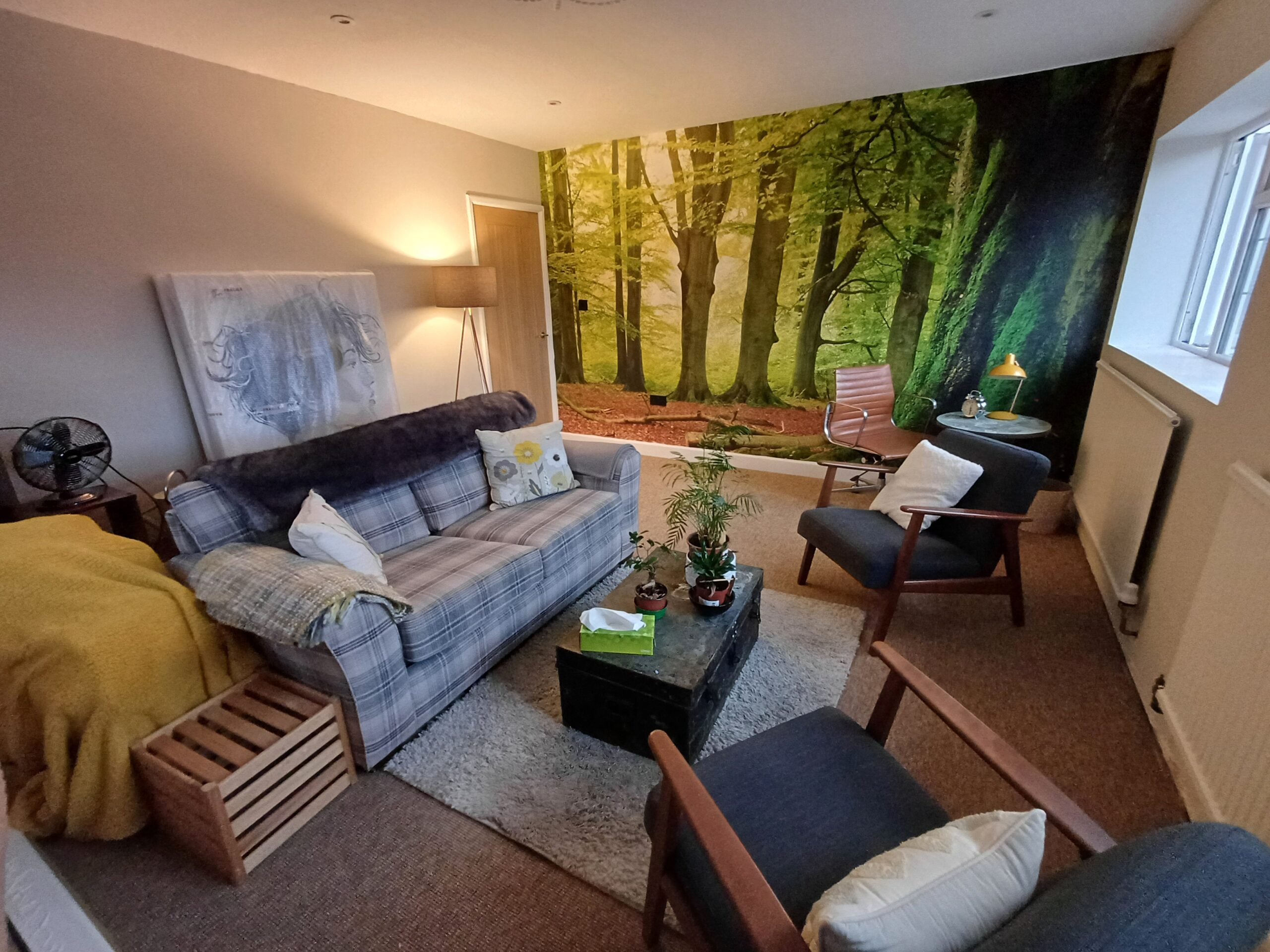 Room with forest wallpaper, a small sofa and two grey armchairs