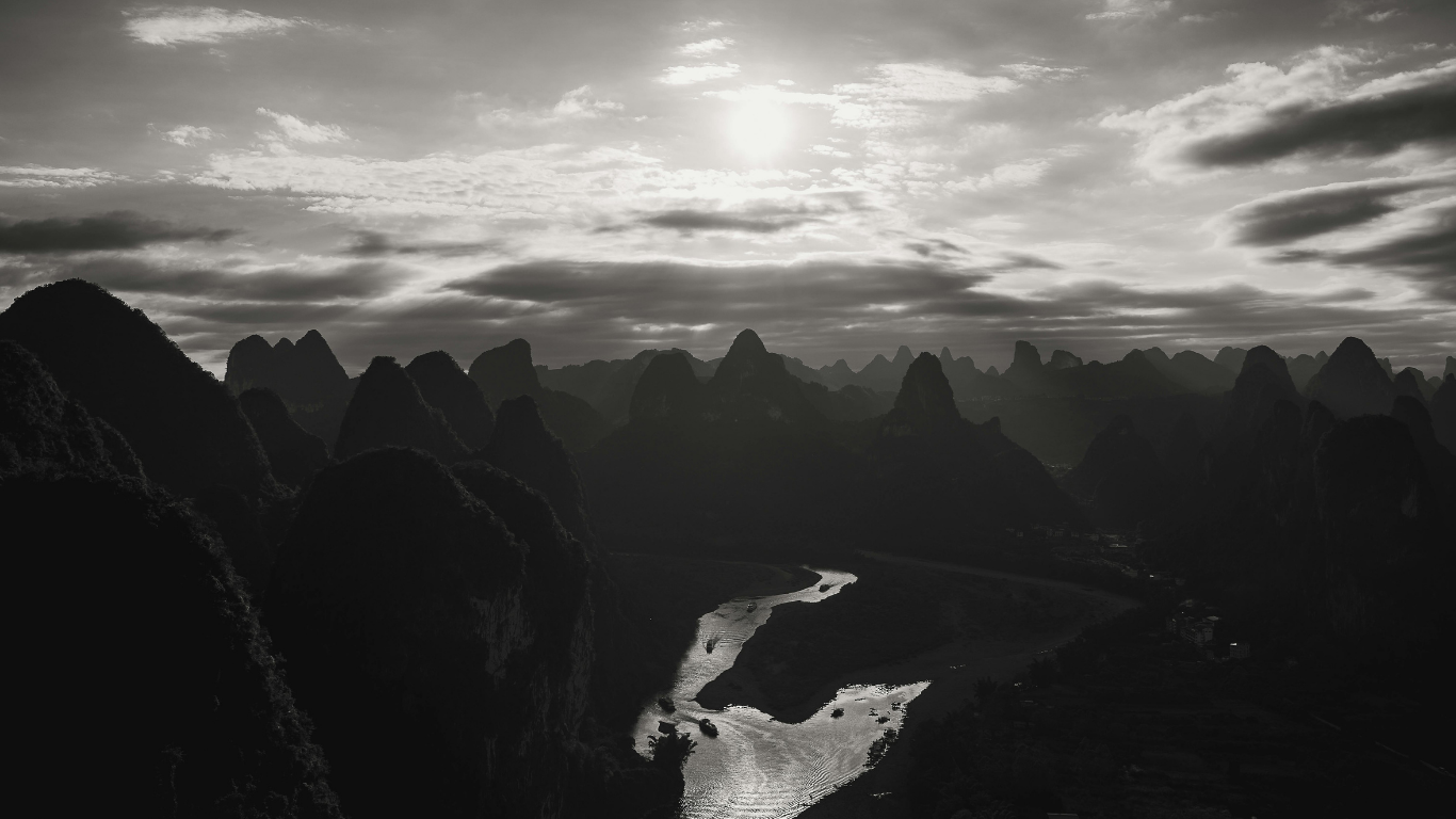 Why we lie. Black and white photograph of valley, sky light clouds and sun glimmering through