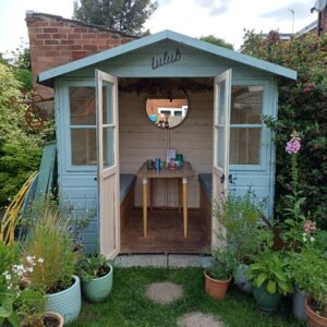 Pretty blue garden room with its doors open, table and mirror visible through the doorway